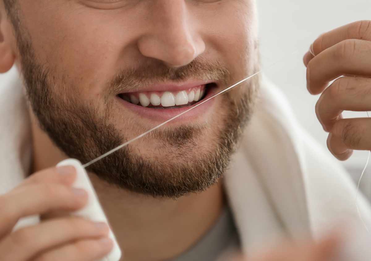 A man is flossing his teeth.
